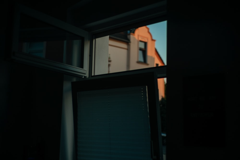 a window in a dark room with a building in the background