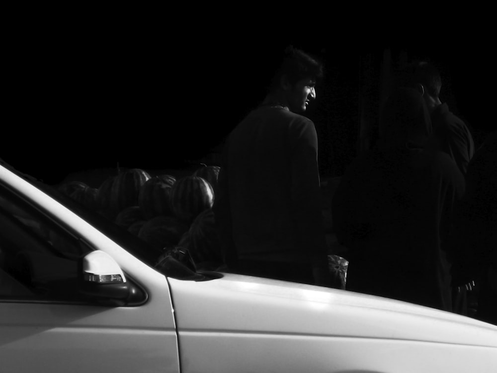 man standing beside white vehicle