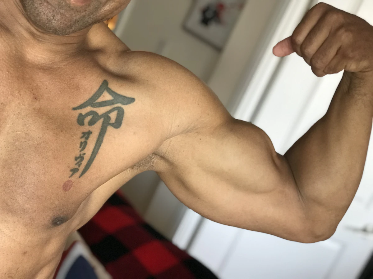 Man flexing his bicep, illustrating the muscle, recovery, and performance goals men pursue with oral and injectable peptide therapy.
