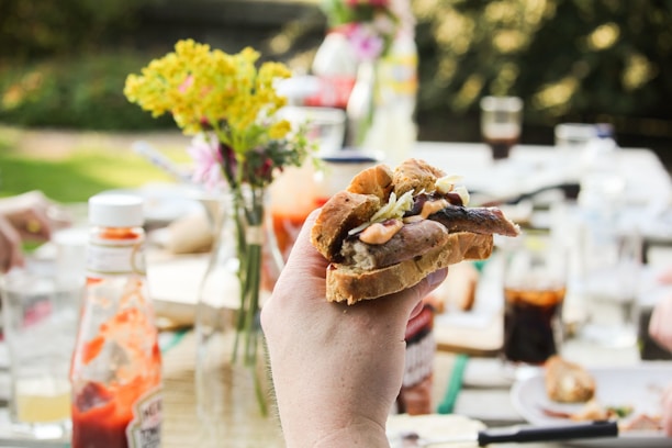 Happy customer enjoying a sausage sandwich at a cozy kitchen table.