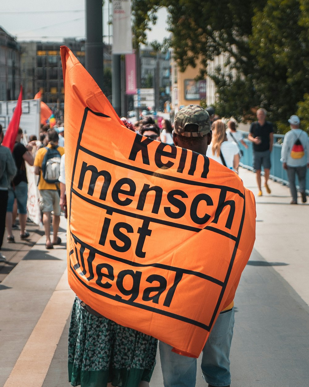 person holding orange and black banner