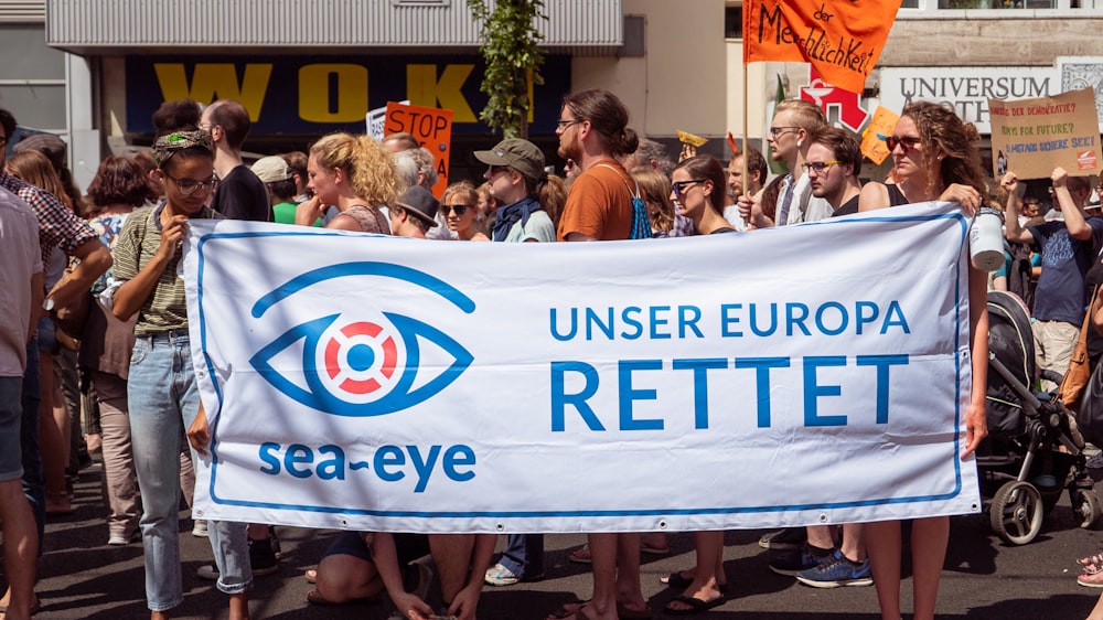 persone per strada mentre tengono in mano lo striscione Sea-Eye Unser Europa Rettet