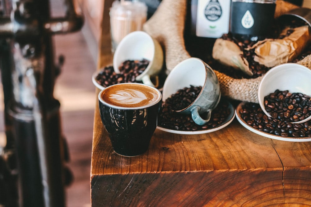 mug with latte art beside tilted mugs with coffee beans