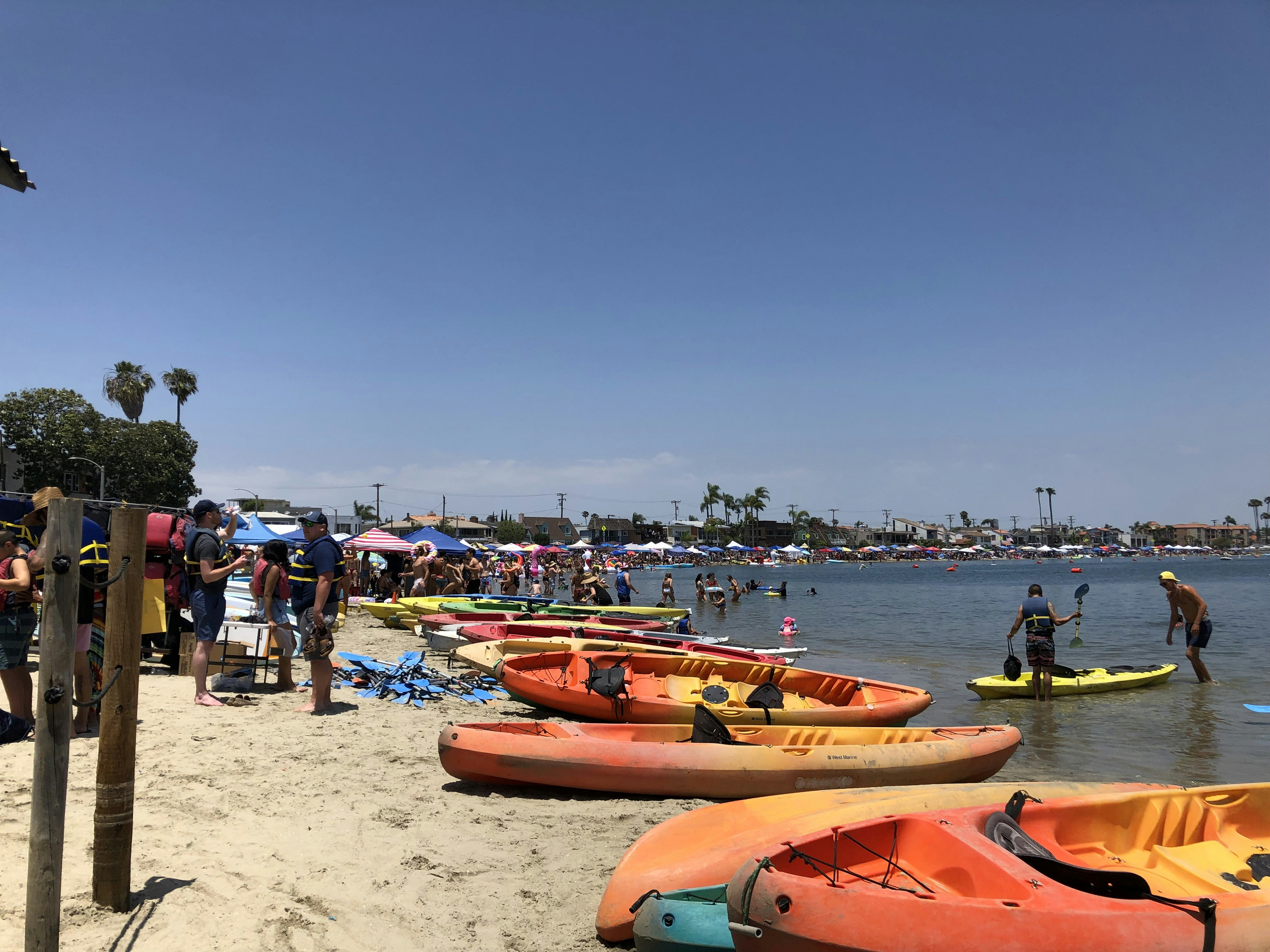 people and boats at the beach during day
