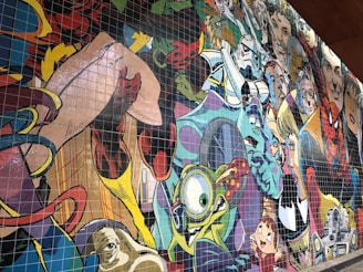 A colorful mural featuring a collage of various cartoon and comic book characters, each with distinctive styles and expressions. The artwork is vibrant, filled with lively details and a variety of artistic influences.