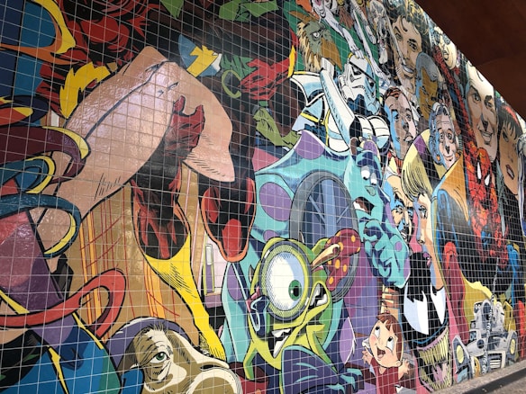A colorful mural featuring a collage of various cartoon and comic book characters, each with distinctive styles and expressions. The artwork is vibrant, filled with lively details and a variety of artistic influences.