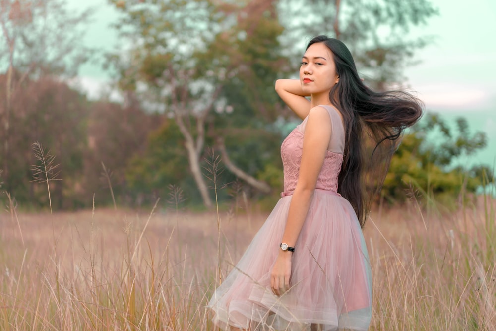 woman wearing pink dress standing on grass field