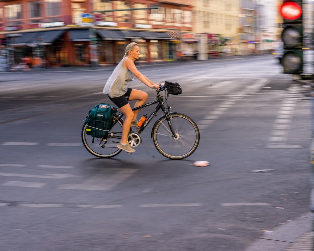 woman wearing grey tank top riding bicycle on road