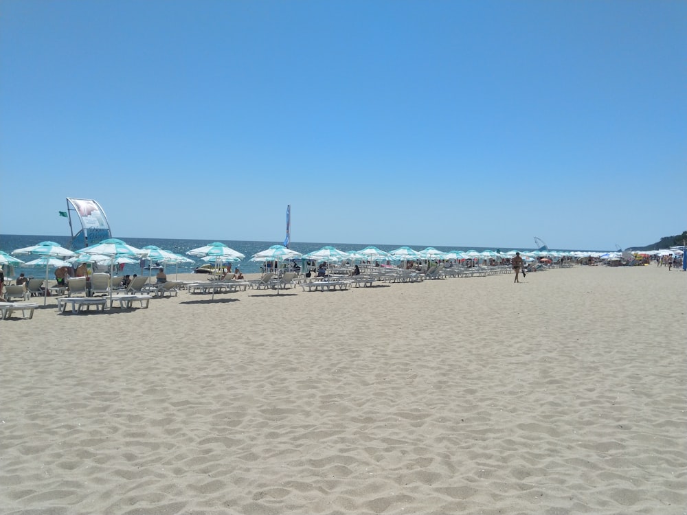 Una playa llena de muchas sillas de jardín y sombrillas