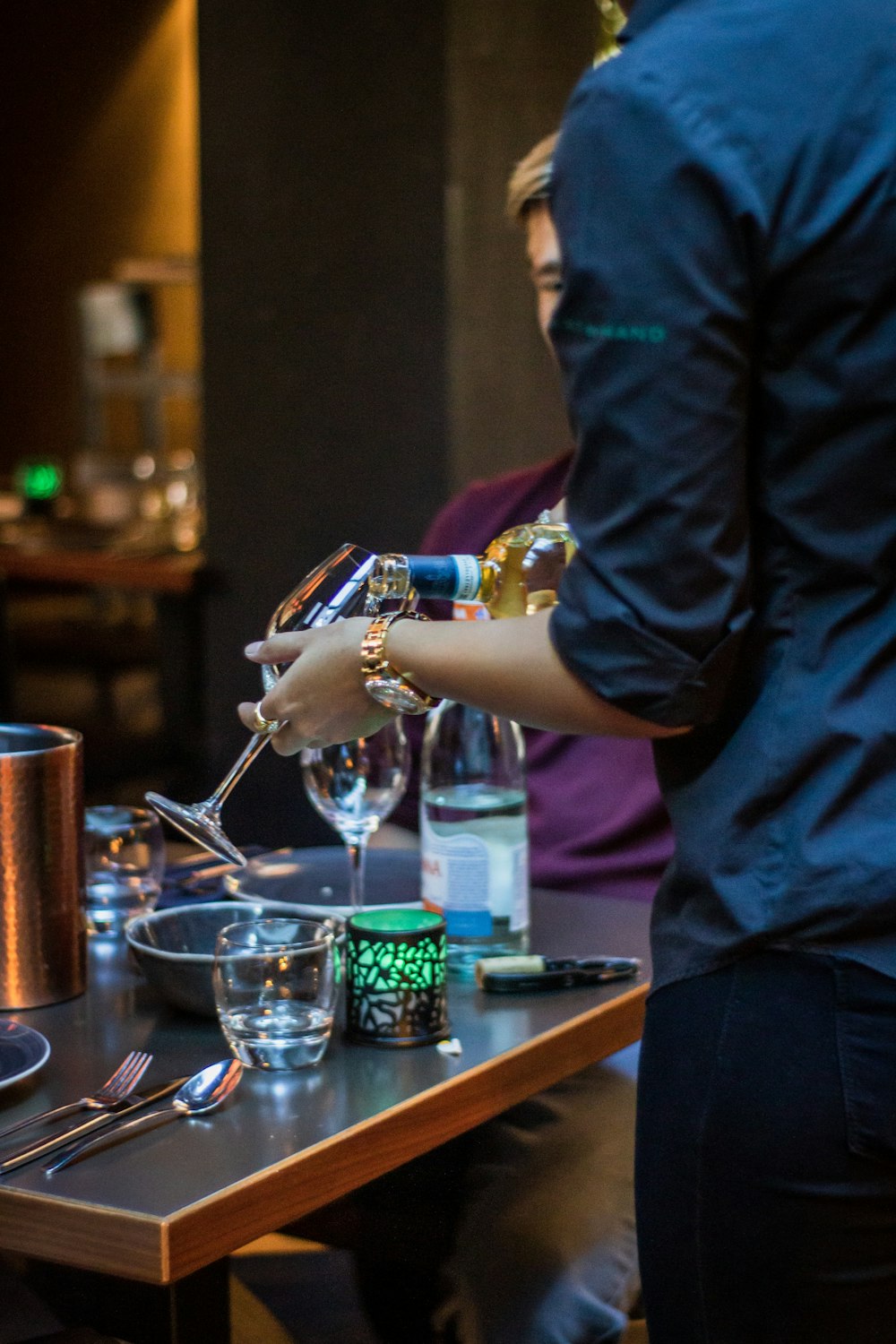 person putting wine in wine glass