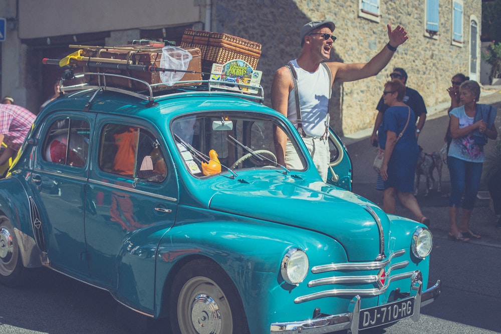 man wearing white tank top shouting beside vehicle