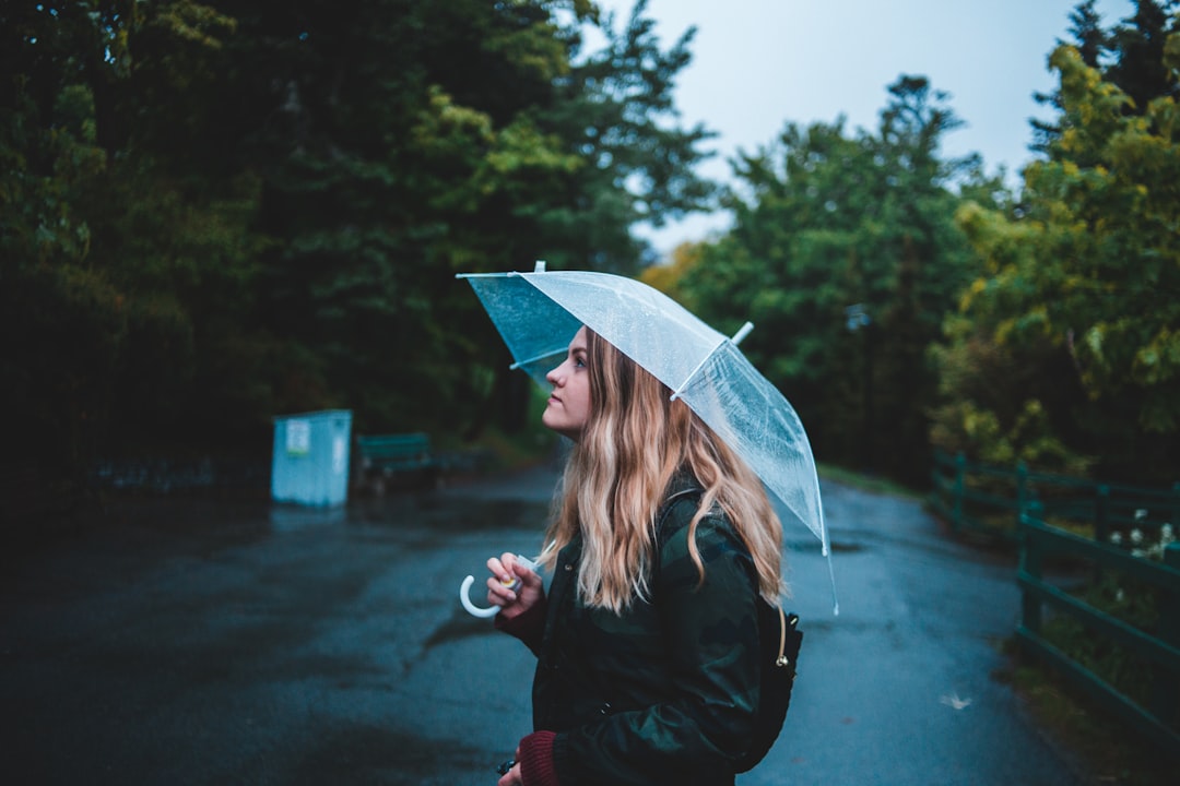 woman holding umbrella while standing in middle of road