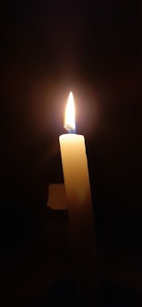 A softly glowing candle flickering gently in a dimly lit room, evoking warmth and intimacy.