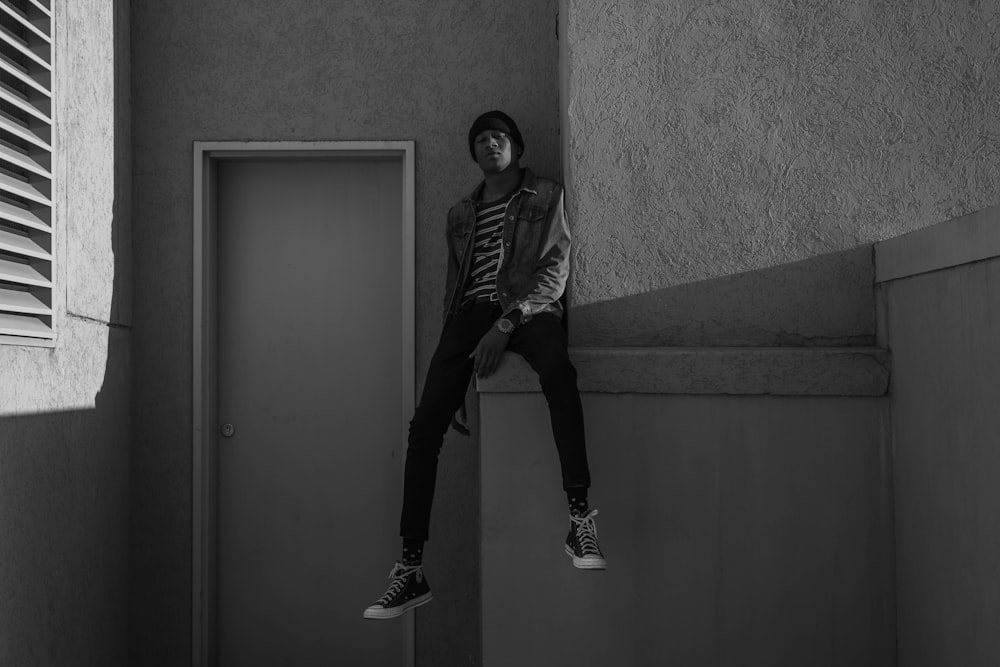 grayscale photography of man sitting near door