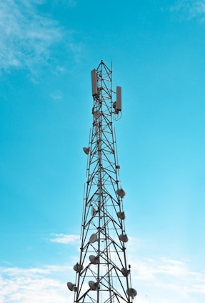 Communication towers with Ubiquiti antennas under a clear blue sky illuminating the horizon.