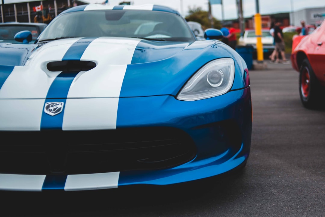 parked blue and white coupe beside red car