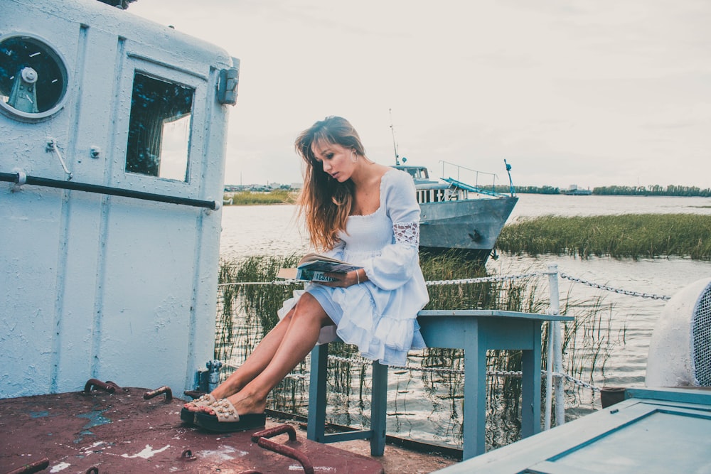 a woman sitting on a boat looking at a book