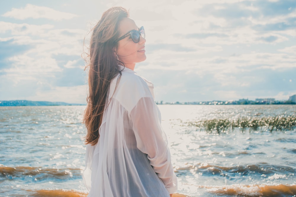 Mujer en camisa de vestir blanca frente al mar