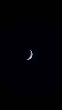 An elegant crescent moon glowing softly against a deep midnight blue sky sprinkled with tiny gold constellations.