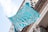 A turquoise and white flag with intricate designs and the text 'Rhode Island School of Design' in white waves in front of a classical building facade.