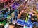 A complex array of computer motherboards and circuit boards is organized in a sprawling grid layout. Bright, multicolored LED lights illuminate the scene, casting vibrant reflections and creating an intricate, high-tech pattern. Wires and electronic components are interwoven, contributing to an aesthetic that resembles a miniature cityscape.