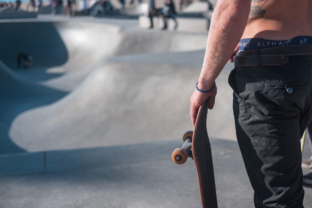 shallow focus photo of person holding black skateboard