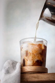 Close-up of a creamy iced coffee with a swirl of milk on top in a clear glass