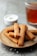Rectangular pieces of fried or baked snacks are stacked on a ceramic plate, sprinkled with coarse salt. A small bowl of creamy white dipping sauce with herbs sits in the background, alongside a glass of amber-colored tea.