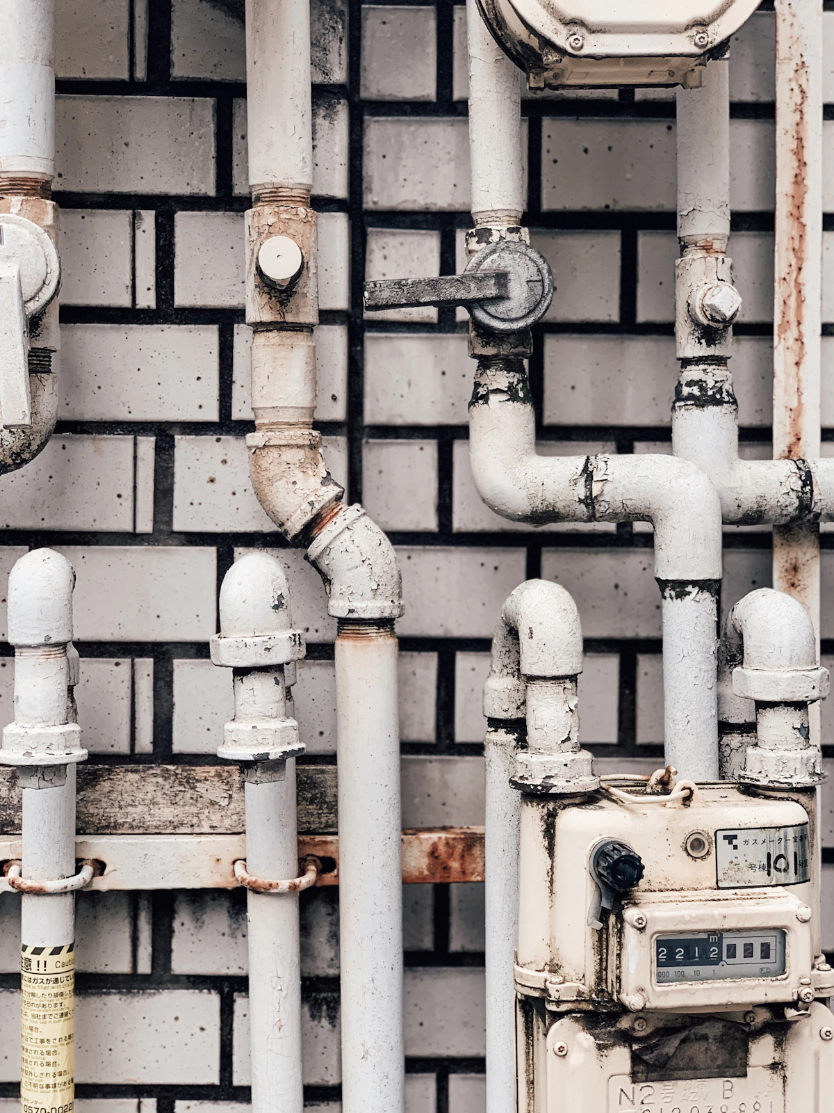White-painted pipes and a meter on a white brick wall