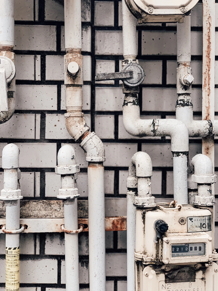 White-painted pipes and a meter on a white brick wall