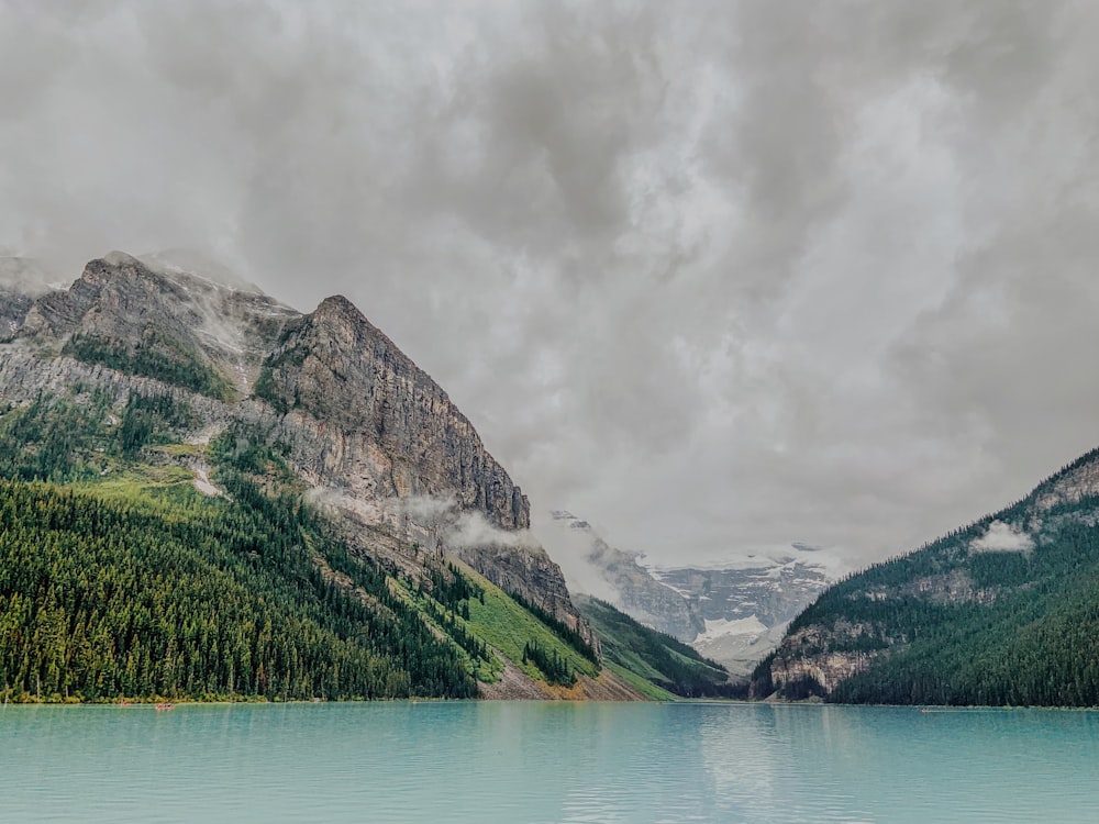 body of water in front of mountain under cloudy sky