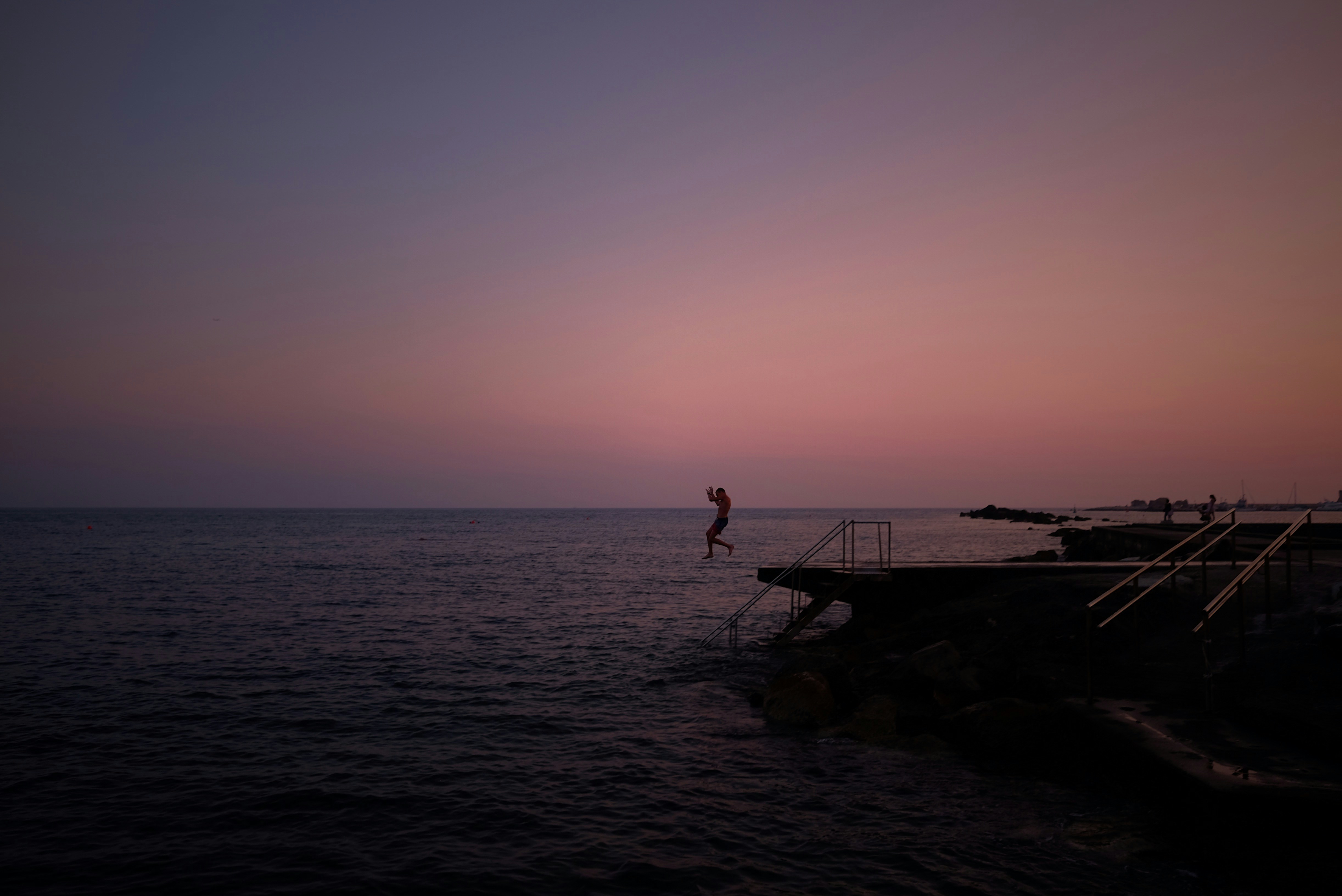 person diving in the sea from a platform