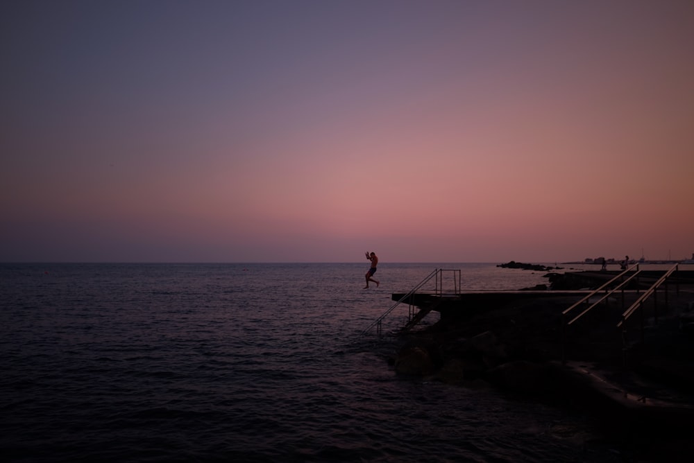 person diving in the sea from a platform