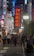 A bustling urban street scene at night, filled with numerous people walking along a brightly lit avenue. Illuminated signs in various vibrant colors including red, blue, and green line the buildings, advertising different establishments. One prominent sign reads 'I ♥️ KABUKI-CHO' in large red letters. The atmosphere is lively, with a mixture of locals and tourists, and the lights create a dynamic and colorful ambiance.