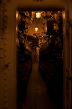 A skilled crew member inspecting a ship's engine room under bright industrial lighting.