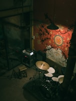 Fabs tuning his drum kit in a minimalist room with gray and black tones.