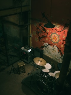 Fabs tuning his drum kit in a minimalist room with gray and black tones.