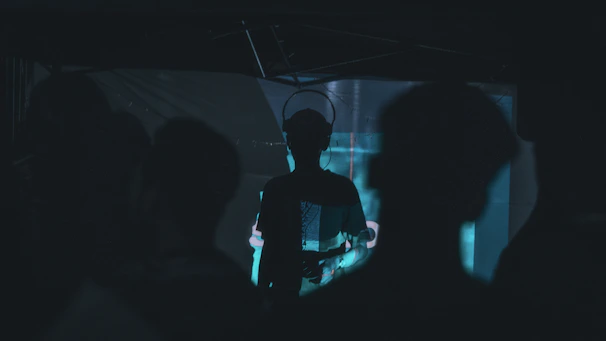 High-contrast shot of an immersive listening party, silhouettes blending with the stark architectural lines.