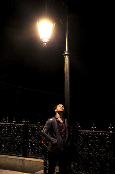 A sleek urban jacket hanging on a city street lamp at dusk.