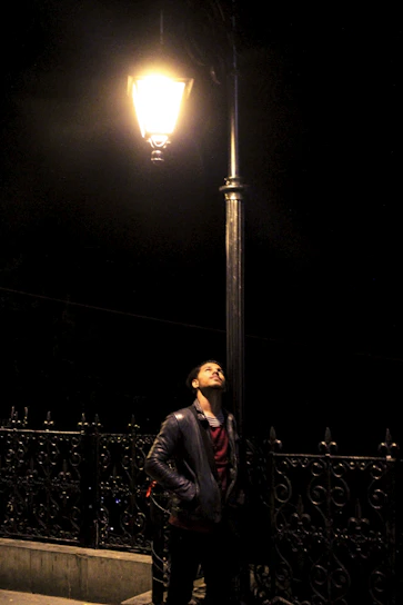 A sleek urban jacket hanging on a city street lamp at dusk.
