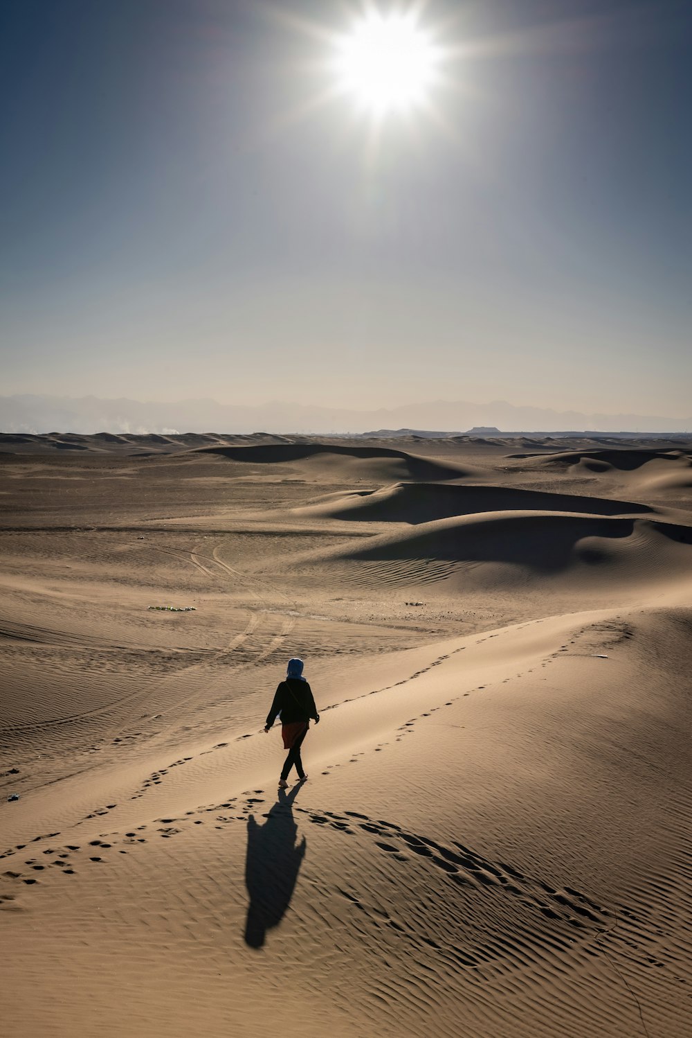 person walking on desert under clear blue sky