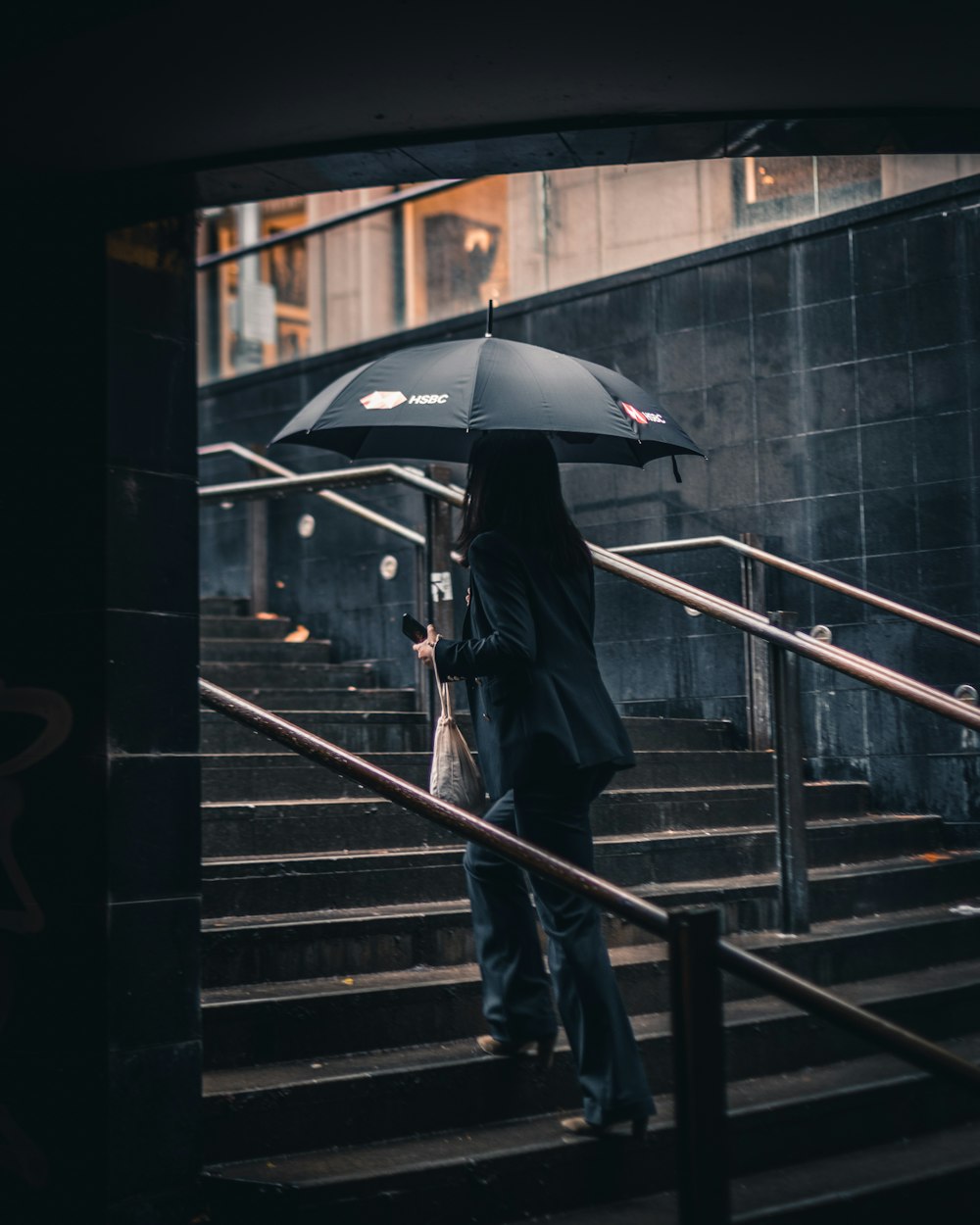 woman walking using umbrella going up on stairs