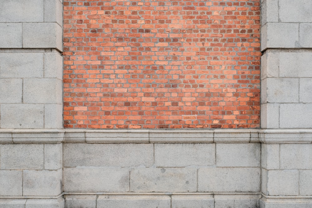 a person sitting on a bench in front of a brick wall