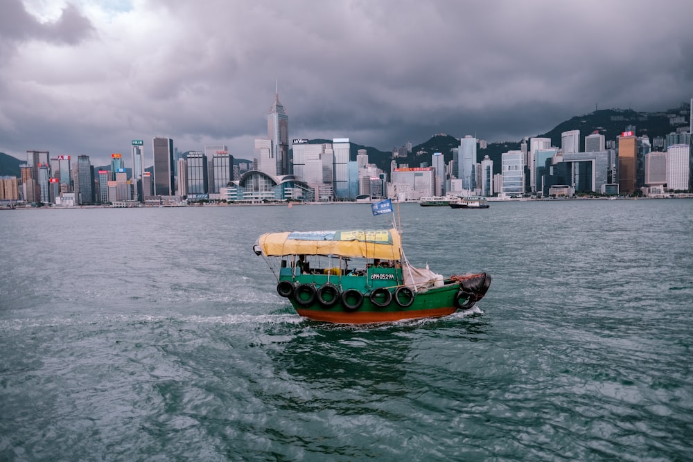 green and red boat on body of water near city