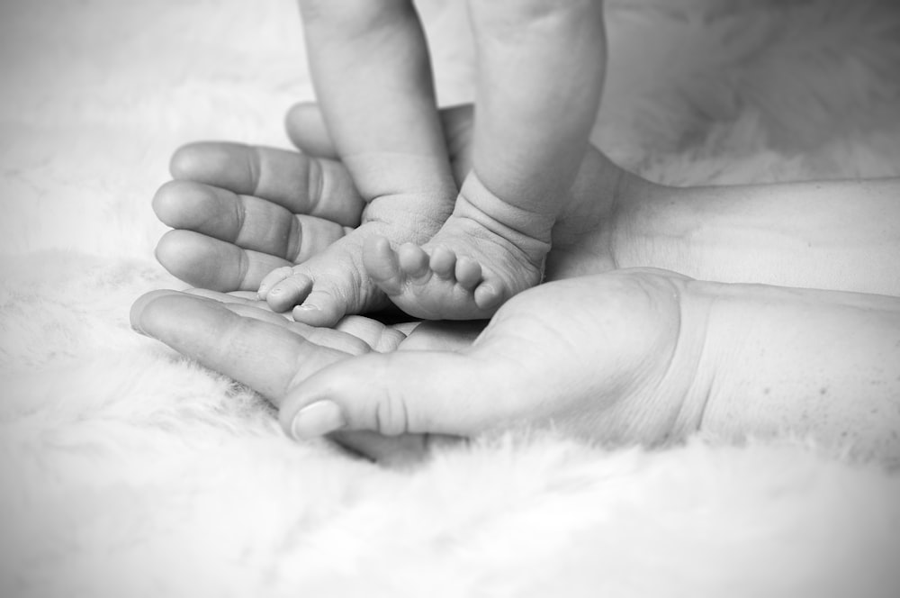 grayscale photo of baby's foot on human palm