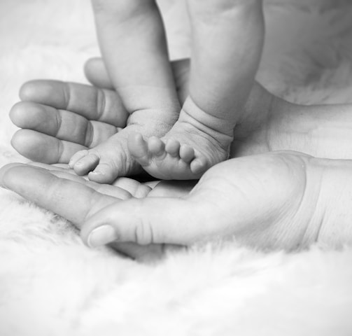 grayscale photo of baby's foot on human palm