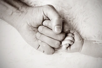 a close up of a person holding a baby's hand