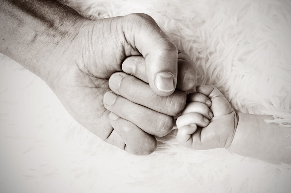 un primo piano di una persona che tiene la mano di un bambino