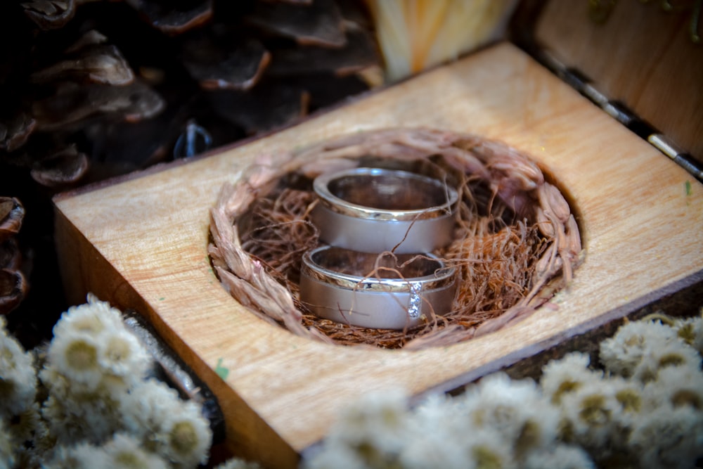 silver-colored wedding bands on wooden case
