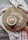 A small white bowl filled with pink Himalayan salt is placed on a round wooden cutting board. The salt is spilled slightly on the board. A red and white checkered cloth is draped around the board, creating a rustic and cozy atmosphere.